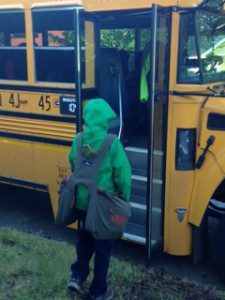 Young boy getting onto a school bus with BackTpack