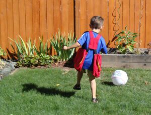 Young boy wearing BTP Mini and playing kickball