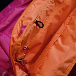 Detail photo of BackTpack 3.1 orange interior of magenta bag, showing key fob, interior zipper, pen pockets, and loop for hydration pack