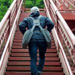 Man climbing long flight of stairs with ease wearing backTpack